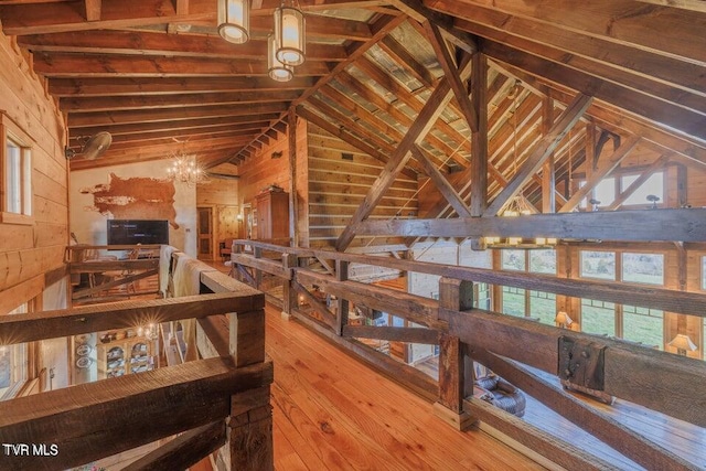 hallway with hardwood / wood-style flooring, an inviting chandelier, wood walls, and vaulted ceiling