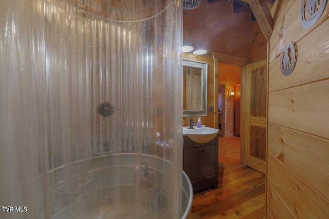 bathroom featuring walk in shower, wood walls, vanity, and wood-type flooring