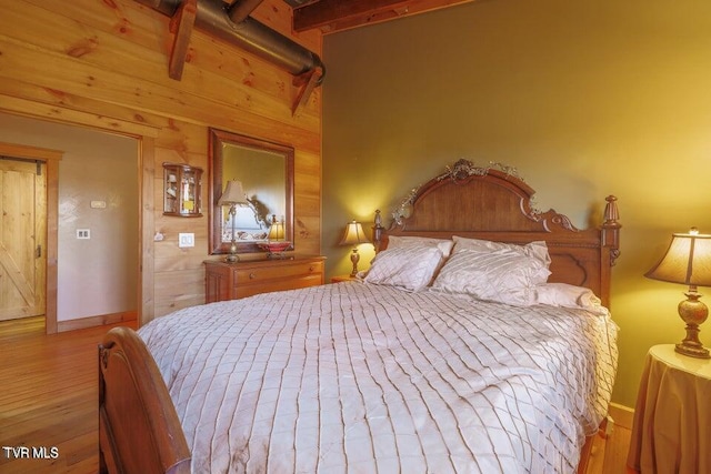 bedroom with light wood-type flooring and beamed ceiling