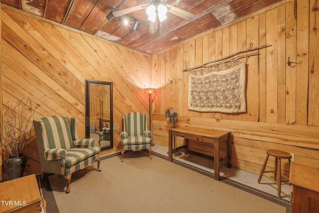 sitting room with wood walls, ceiling fan, carpet, and wood ceiling