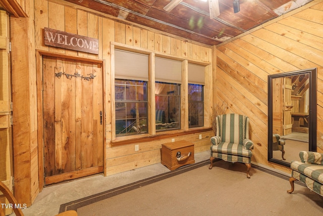 living area featuring wooden ceiling, wooden walls, and carpet