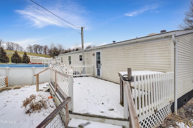 snow covered rear of property with fence