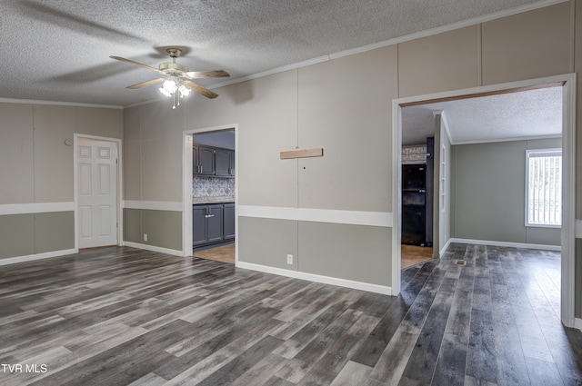 unfurnished room featuring ceiling fan, dark wood-type flooring, a textured ceiling, and ornamental molding