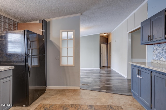 kitchen featuring crown molding, baseboards, freestanding refrigerator, and a textured ceiling