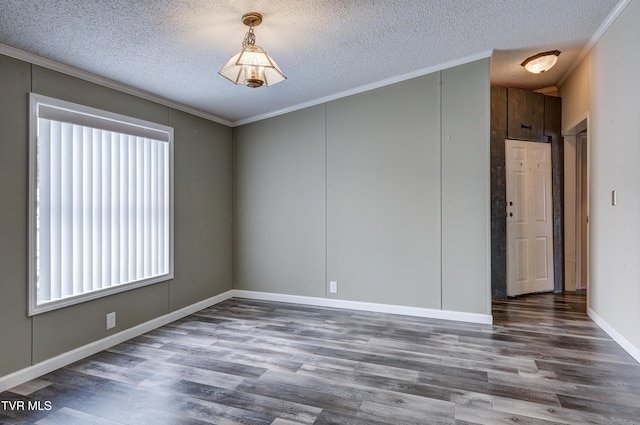 empty room with a textured ceiling, crown molding, and wood finished floors