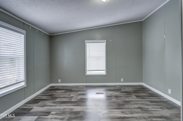 empty room with a textured ceiling, crown molding, and wood finished floors