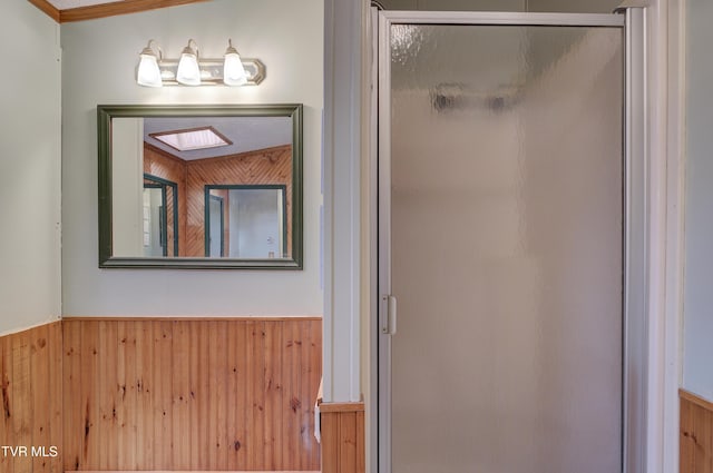 bathroom with a wainscoted wall, wood walls, and a stall shower