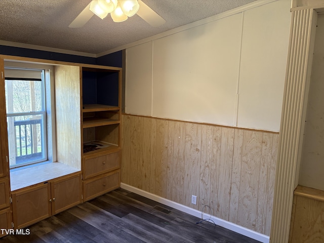 interior space featuring wood walls, a textured ceiling, ceiling fan, and dark wood-style flooring