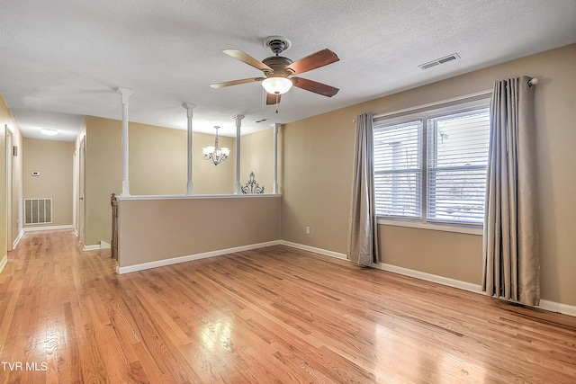 unfurnished room with ceiling fan with notable chandelier, a textured ceiling, and light hardwood / wood-style flooring