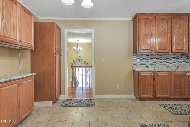 kitchen with light stone countertops, a notable chandelier, crown molding, and tasteful backsplash