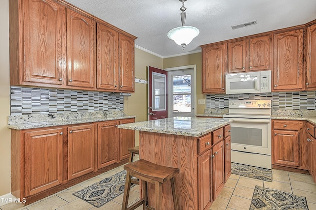 kitchen featuring white appliances, a center island, backsplash, and light stone counters