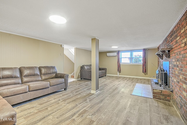 living room with a textured ceiling, light wood-type flooring, crown molding, and an AC wall unit