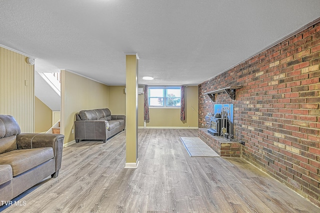 living room with brick wall, a textured ceiling, light hardwood / wood-style flooring, and a wood stove