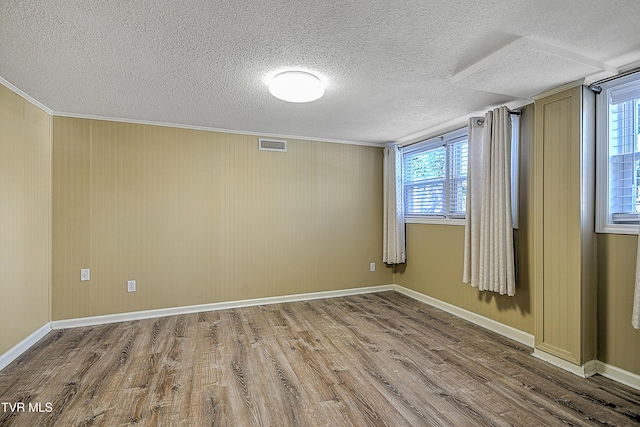 unfurnished room featuring hardwood / wood-style flooring, a textured ceiling, and crown molding