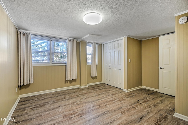 unfurnished bedroom with a textured ceiling, a closet, and hardwood / wood-style floors