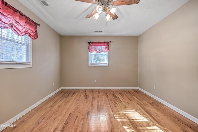 spare room with a textured ceiling, ceiling fan, and light hardwood / wood-style floors