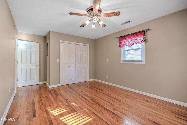 unfurnished bedroom featuring ceiling fan, light hardwood / wood-style floors, and a textured ceiling