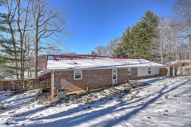 snow covered rear of property featuring central AC