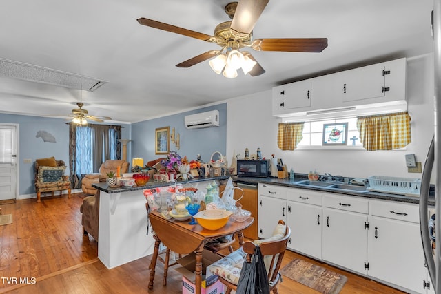 kitchen featuring sink, white cabinetry, a wall mounted air conditioner, and kitchen peninsula