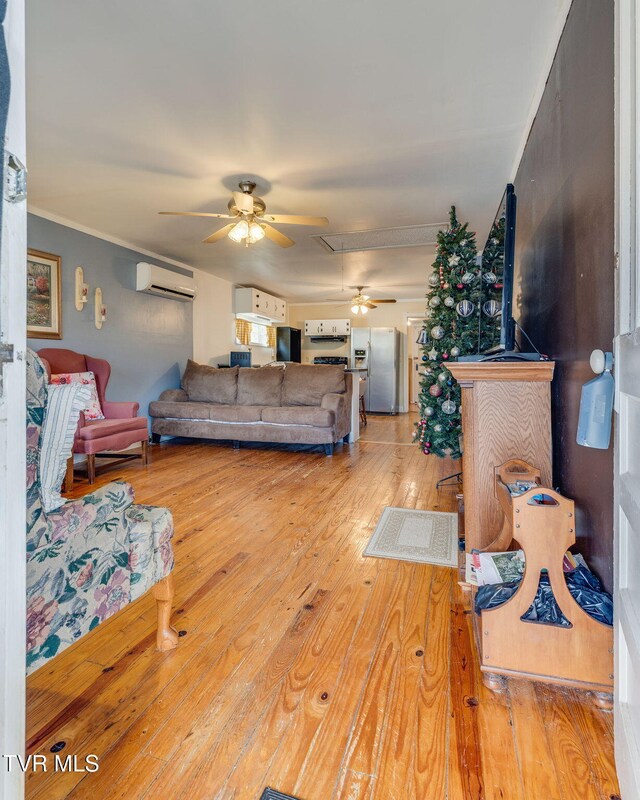 living room featuring a ceiling fan, hardwood / wood-style flooring, crown molding, and a wall mounted AC