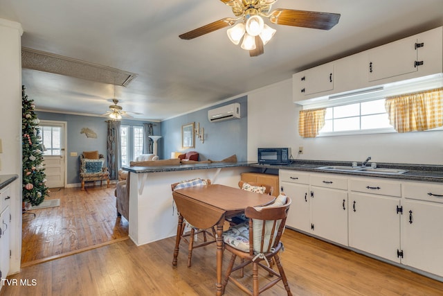 kitchen with dark countertops, an AC wall unit, a sink, and a peninsula