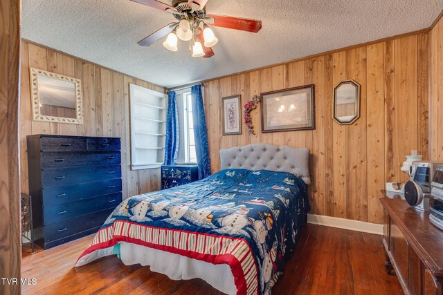 bedroom featuring a textured ceiling, wood walls, a ceiling fan, baseboards, and wood-type flooring