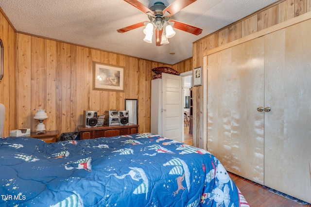 bedroom featuring a textured ceiling, wood walls, and wood finished floors