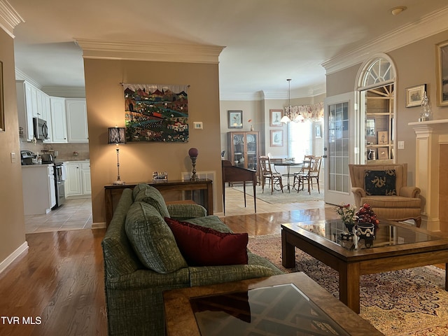 living room featuring a notable chandelier, light wood-style flooring, and crown molding