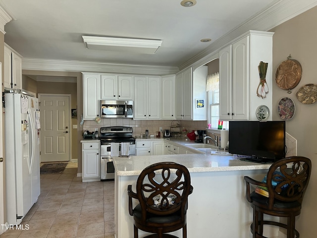 kitchen featuring a breakfast bar area, stainless steel appliances, a peninsula, a sink, and white cabinets