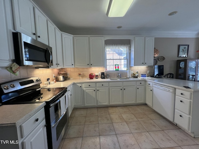 kitchen featuring a peninsula, white cabinets, light countertops, appliances with stainless steel finishes, and decorative backsplash