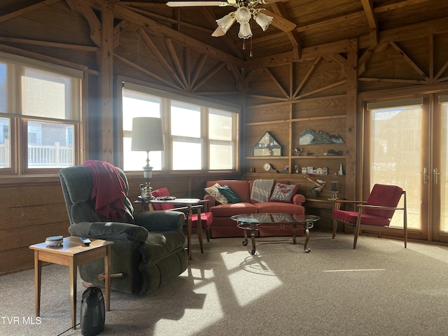 sitting room featuring carpet flooring, a ceiling fan, and wooden walls