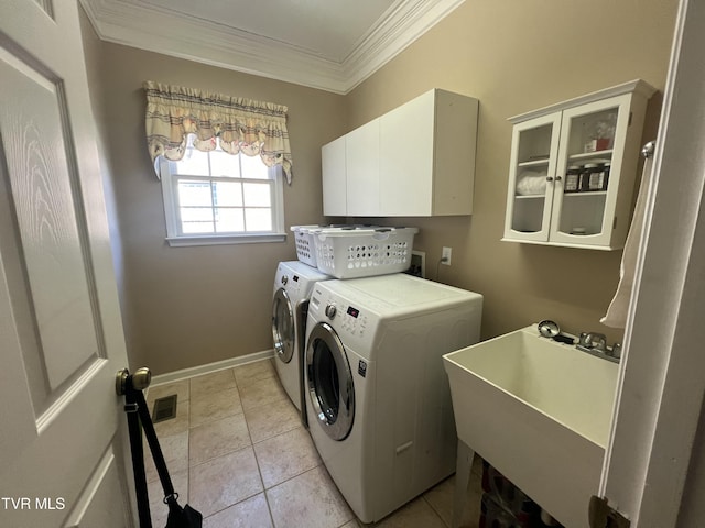 clothes washing area with cabinet space, light tile patterned floors, ornamental molding, washer and dryer, and a sink