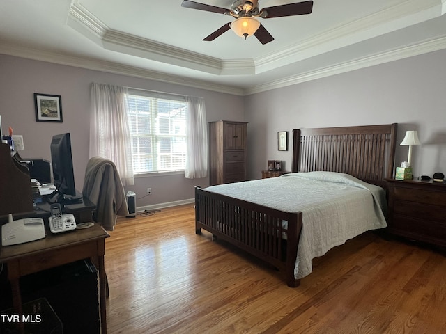 bedroom featuring a tray ceiling, wood finished floors, a ceiling fan, and crown molding