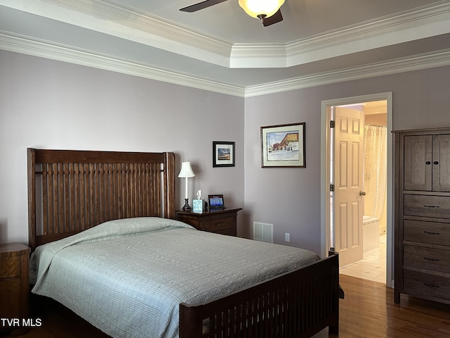 bedroom with visible vents, connected bathroom, ceiling fan, wood finished floors, and crown molding