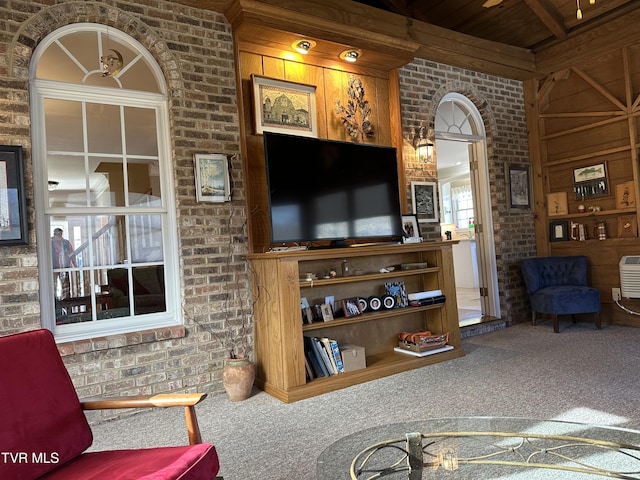 carpeted living area with brick wall