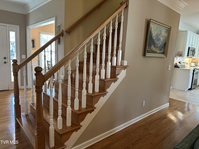 staircase featuring crown molding, baseboards, and wood finished floors