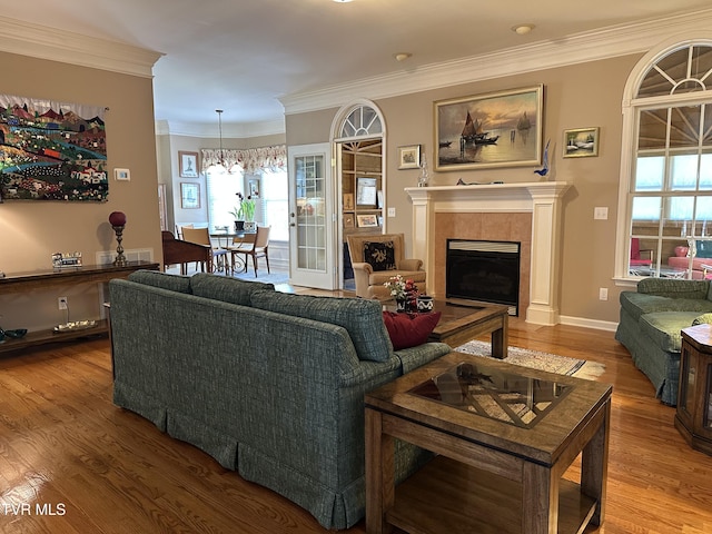 living area featuring a notable chandelier, a fireplace, ornamental molding, and wood finished floors