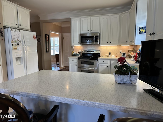 kitchen with light countertops, backsplash, appliances with stainless steel finishes, ornamental molding, and white cabinetry