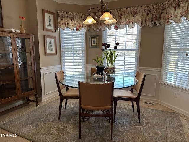 tiled dining room with a wainscoted wall, visible vents, and a decorative wall