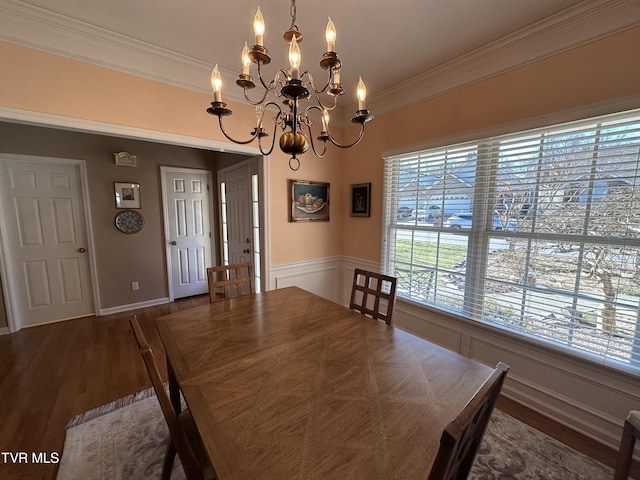 unfurnished dining area with crown molding, a decorative wall, an inviting chandelier, and wood finished floors