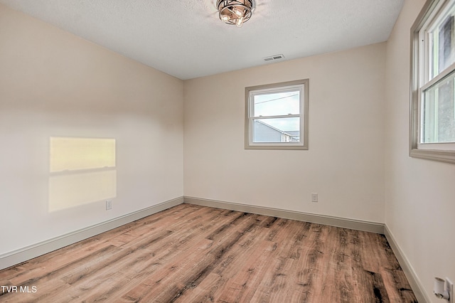 spare room with a textured ceiling and light hardwood / wood-style flooring