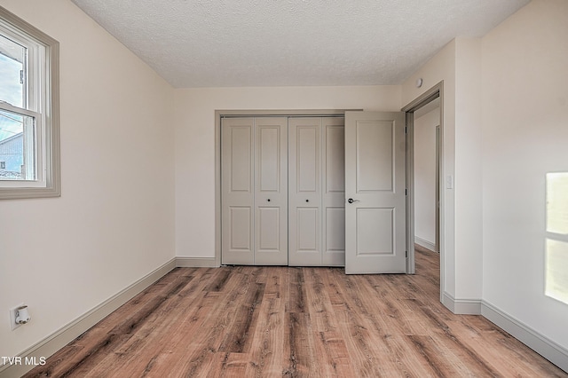 unfurnished bedroom featuring light hardwood / wood-style floors, a textured ceiling, and a closet