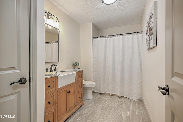 bathroom with a textured ceiling, toilet, and vanity