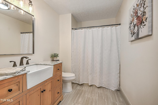 bathroom featuring a textured ceiling, toilet, and vanity