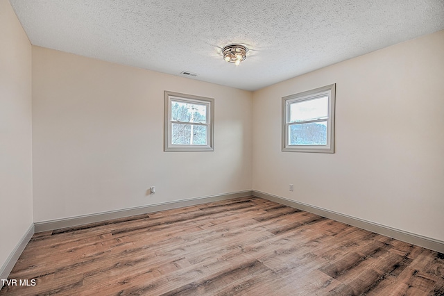 unfurnished room featuring a textured ceiling, light hardwood / wood-style flooring, and a healthy amount of sunlight