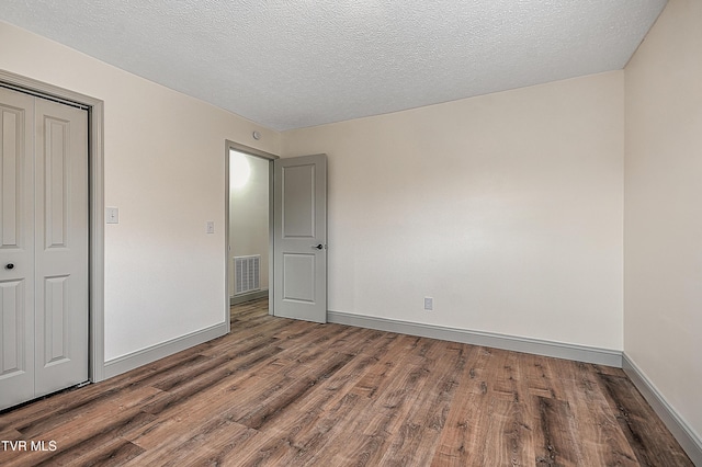 unfurnished bedroom featuring a closet, a textured ceiling, and hardwood / wood-style flooring