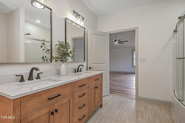 bathroom featuring a textured ceiling, ceiling fan, walk in shower, and vanity