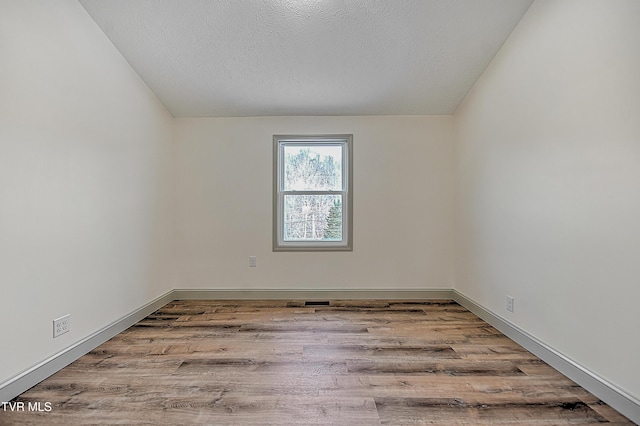 spare room featuring light wood-type flooring and a textured ceiling