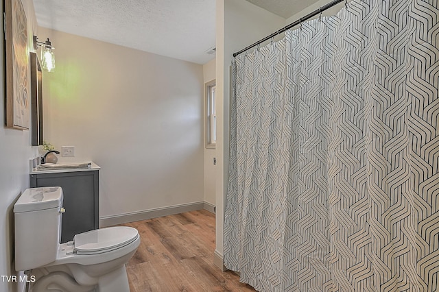 bathroom featuring curtained shower, a textured ceiling, vanity, toilet, and hardwood / wood-style flooring