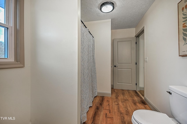 bathroom with a textured ceiling, toilet, and hardwood / wood-style floors